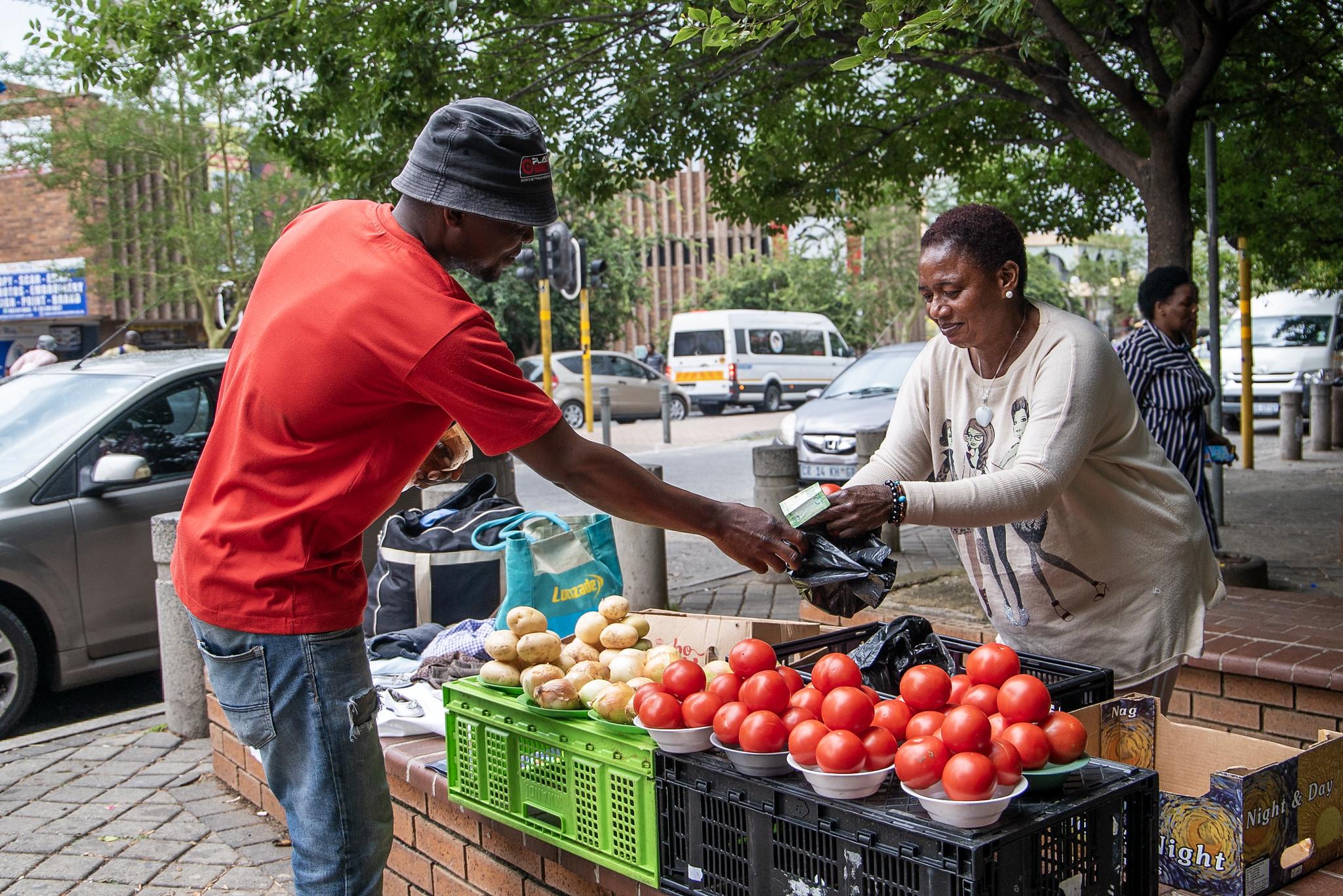 A street seller serving a customer at an outdoor stall in South Africa.